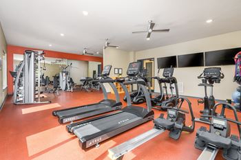 A gym with treadmills, elliptical machines, and other exercise equipment.